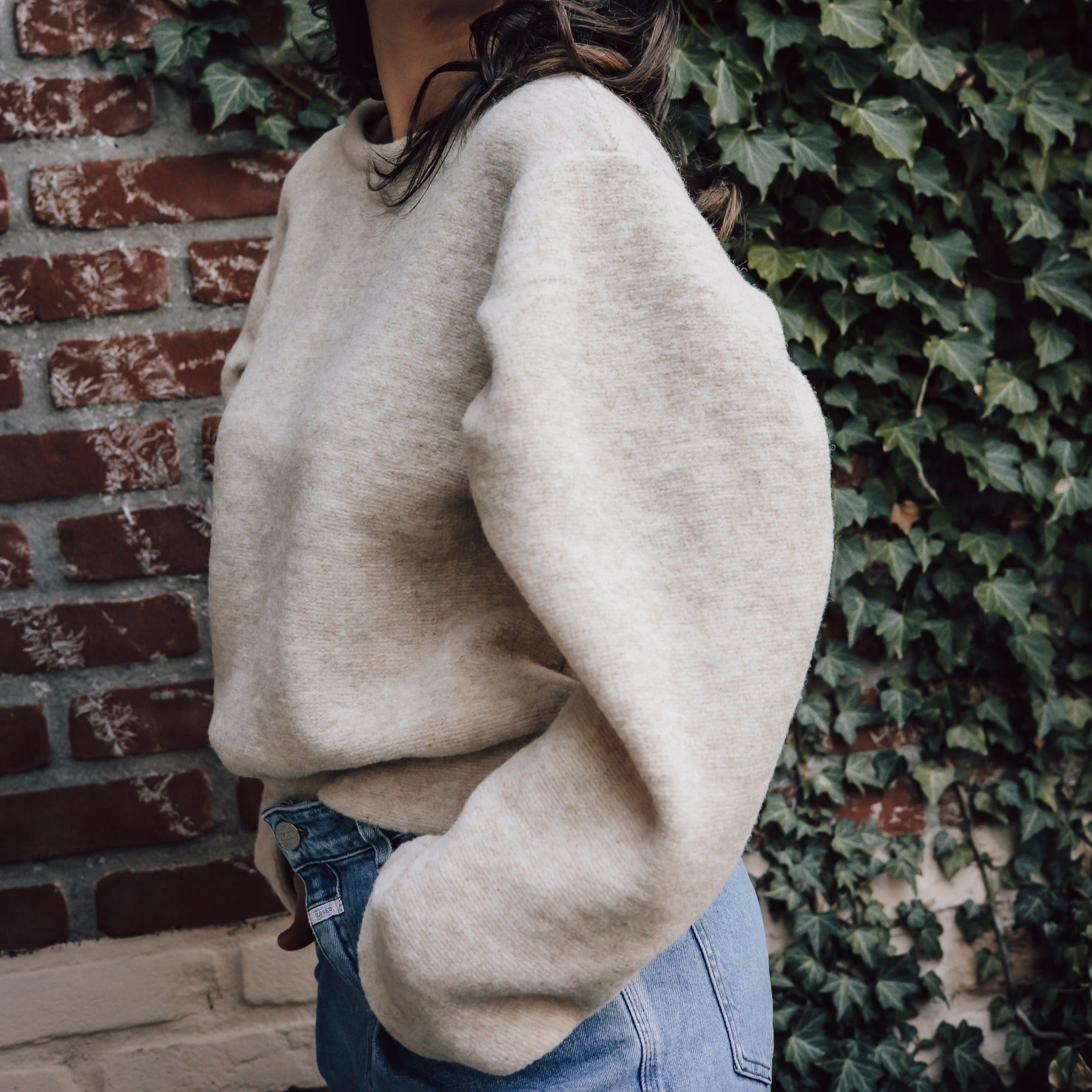Volwasse vrouw draagt beige wollen trui van Alwero met pofmouwen