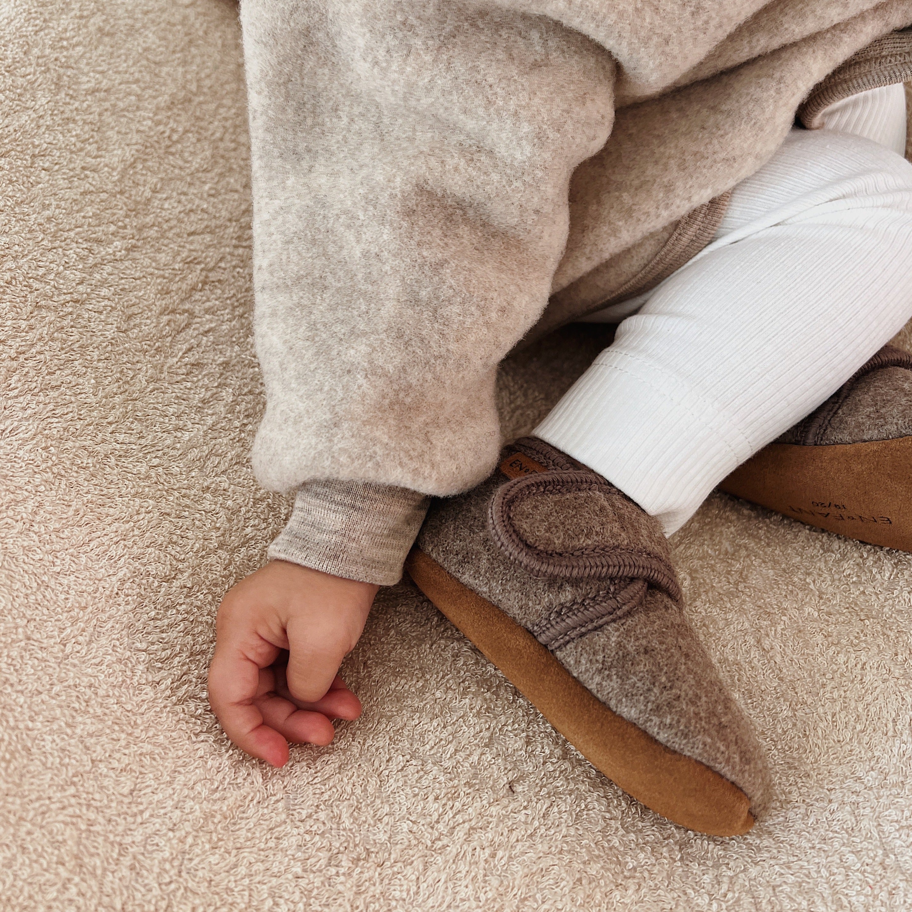Lifestyle zoom in Babyslofjes wool walnut en Engel Natur jasje sand.