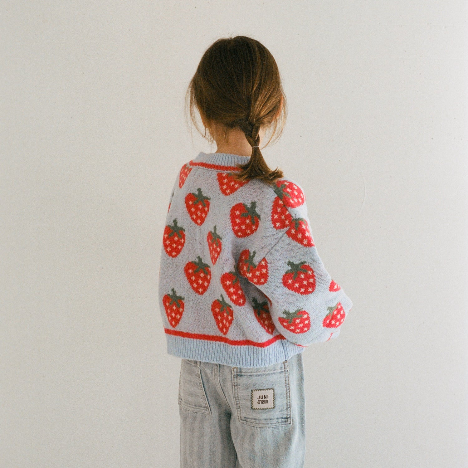 Meisje met aardbeien vestje en broek aan van het merk Juni