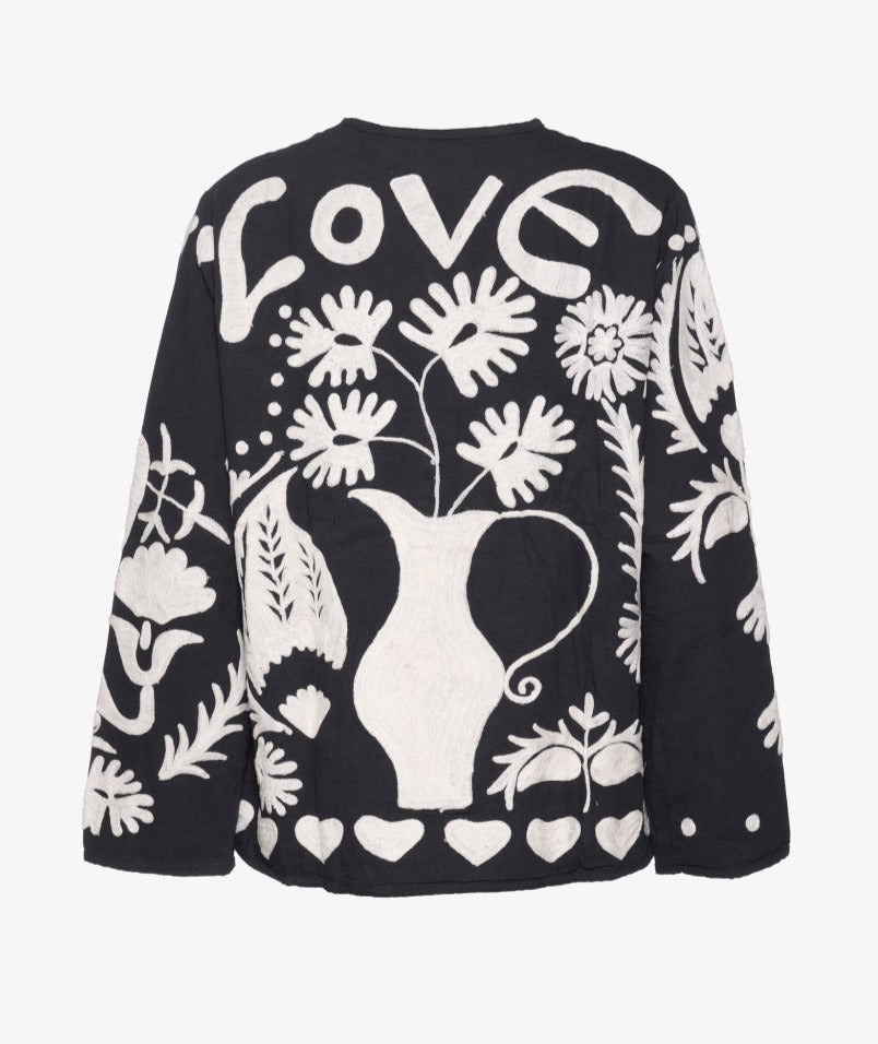 Maggie Suzani Jacket heeft een casual fit met twee zakken aan de voorkant. Het jasje is gemaakt van katoenen canvas. Je ziet over het gehele jasje een opvallende Suzani borduurwerk met klaproosbloemen, harten en een prachtige Indiase pauw aan de achterkant. Het borduurwerk is handgemaakt. De naam 'Suzani' komt van het Perzische woord 'su-zan' wat naald betekent.