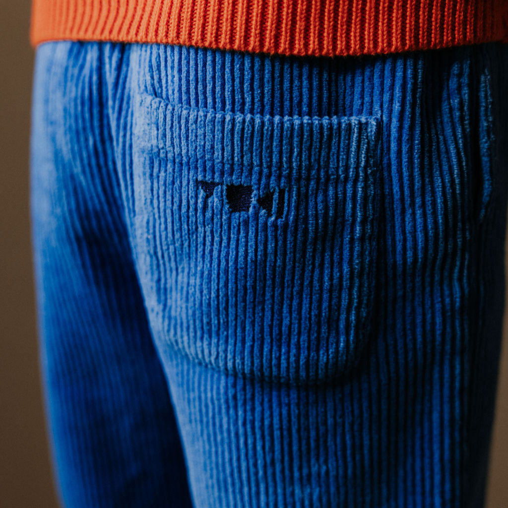 Closeup foto van de achterzak van Blauwe corduroy broek met een wit strikje voor kinderen van het merk Yuki