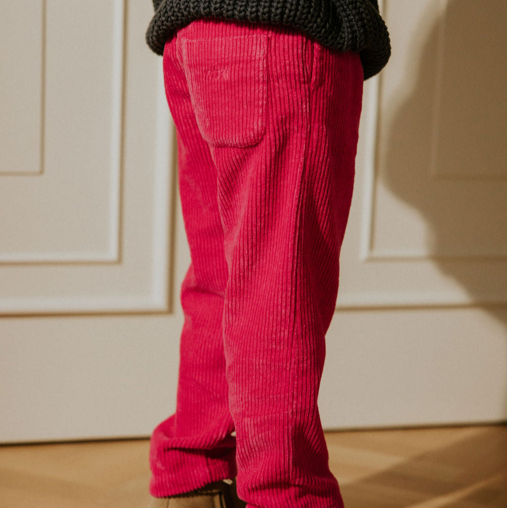 Closup van Fuchsia corduroy broek aan bij een kind met stoere schoenen erbij