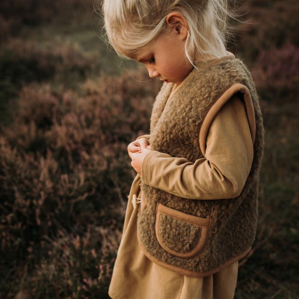 Kind draagt bruine wollen bodywarmer van het merk Alwero