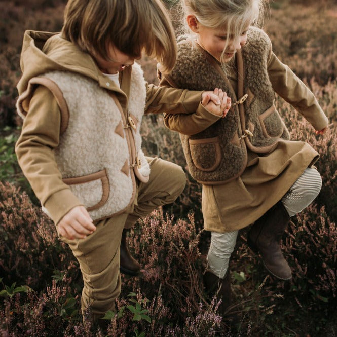 Kind draagt beige wollen bodywarmer van het merk Alwero