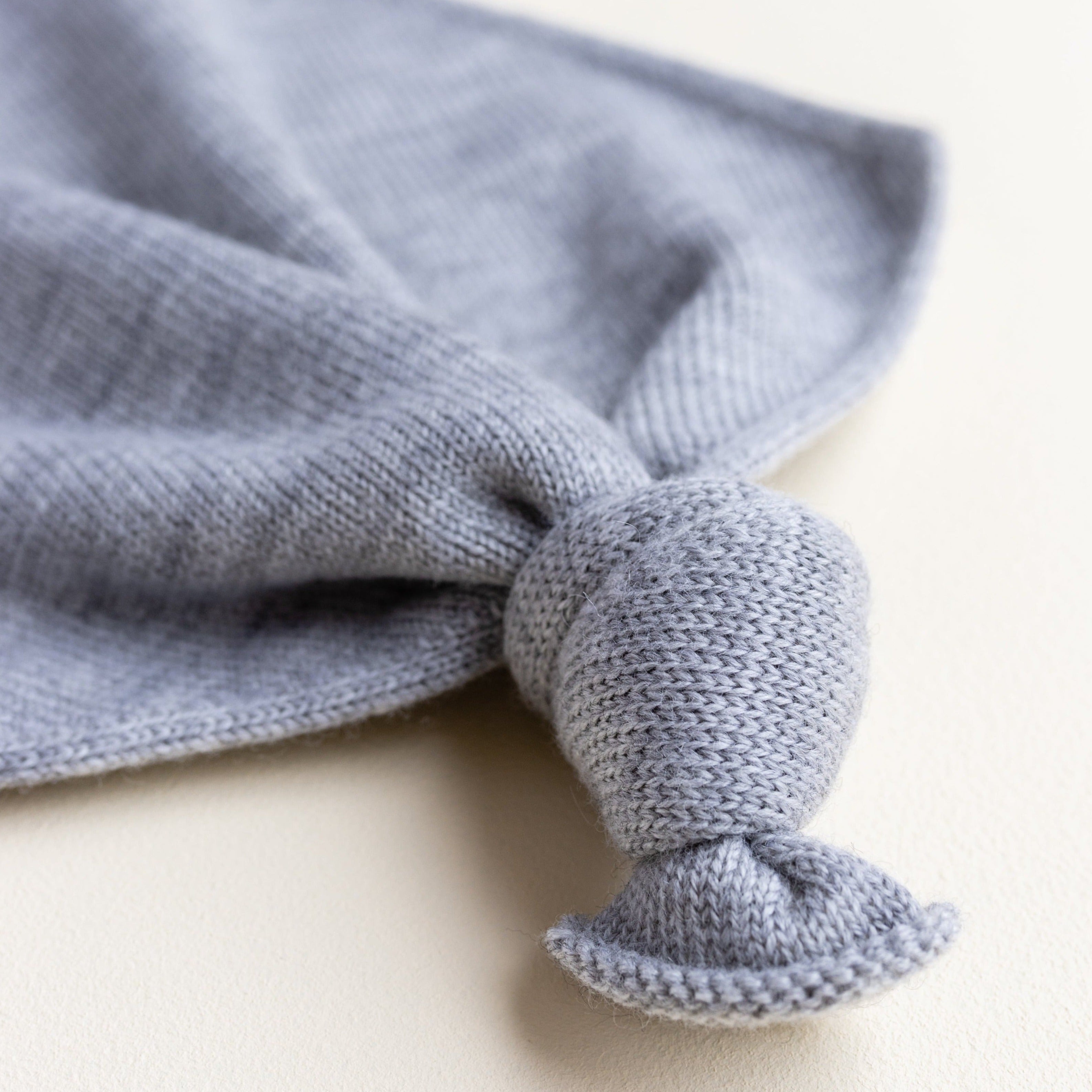 Gebreid speendoekje voor baby's in de kleur Grey Melange van HVID.Gebreid speendoekje voor baby's in de kleur grijs van HVID ingezoomd op knoop.