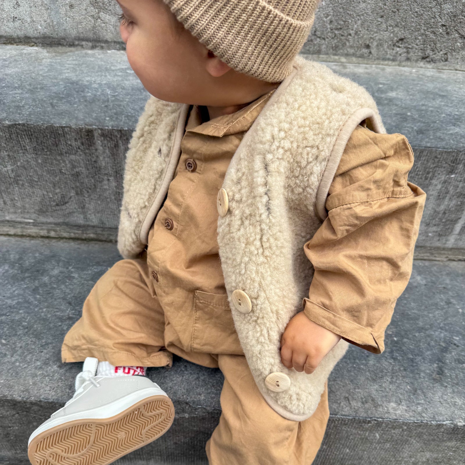 Bodywarmer sand aan bij jongetje op een trap