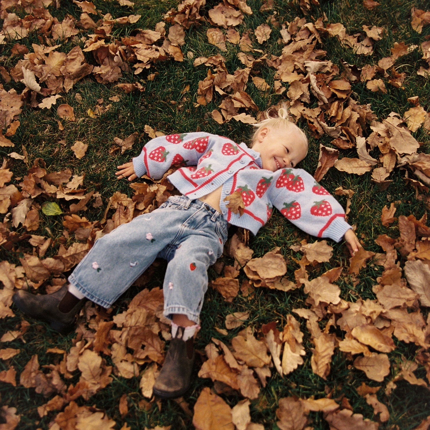 Meisje tussen de bladeren met skies cardigan vest aan van het merk Juni