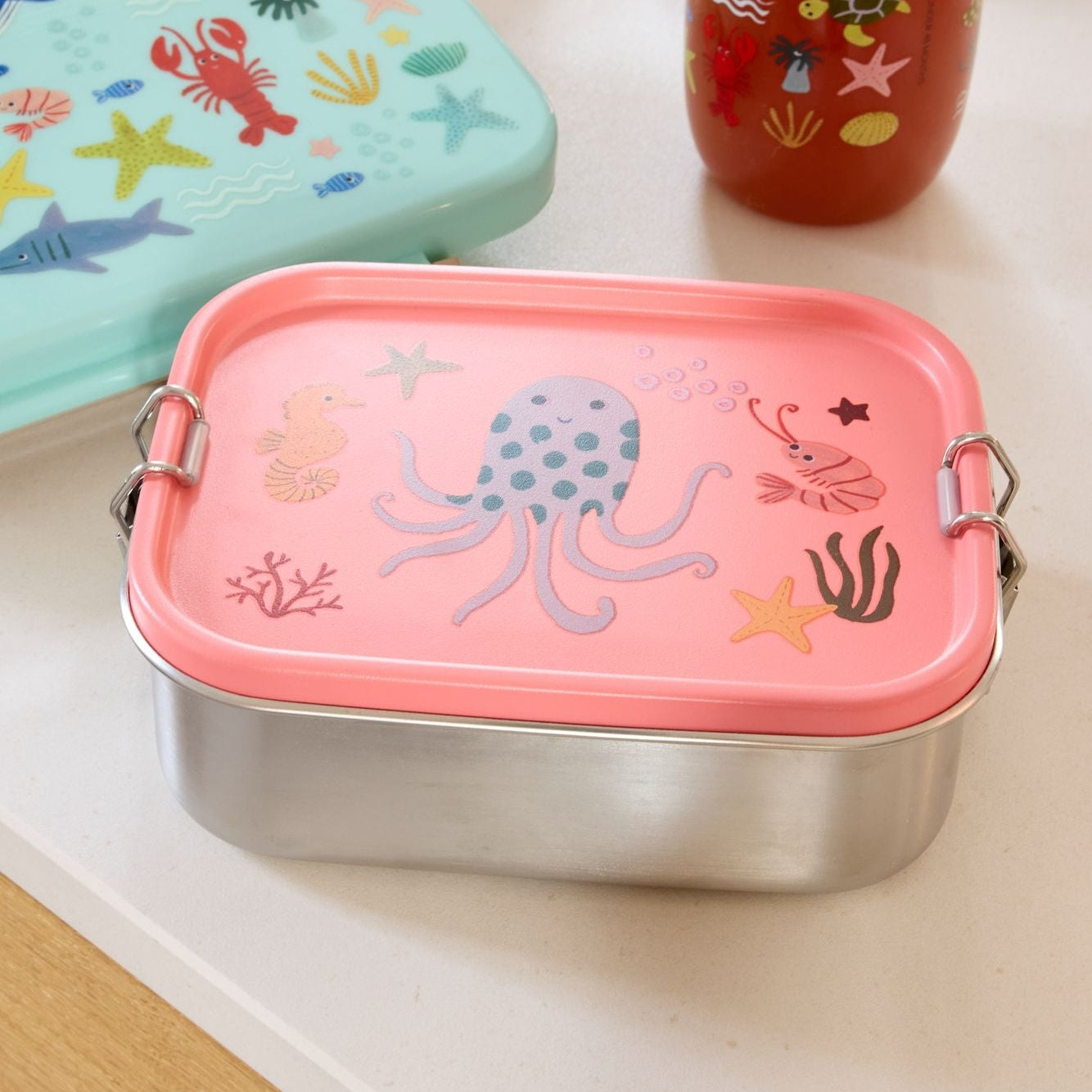 Rose lunchbox roestvrijstaal die op tafel ligt en vanhet merk ricebyrice is