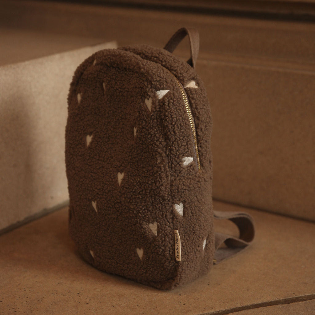 Bruine rugzak teddy stof met witte hartjes op een trap