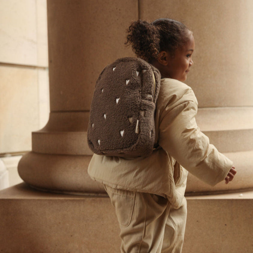 Bruine rugzak teddy stof met witte hartjes bij meisje op de rug