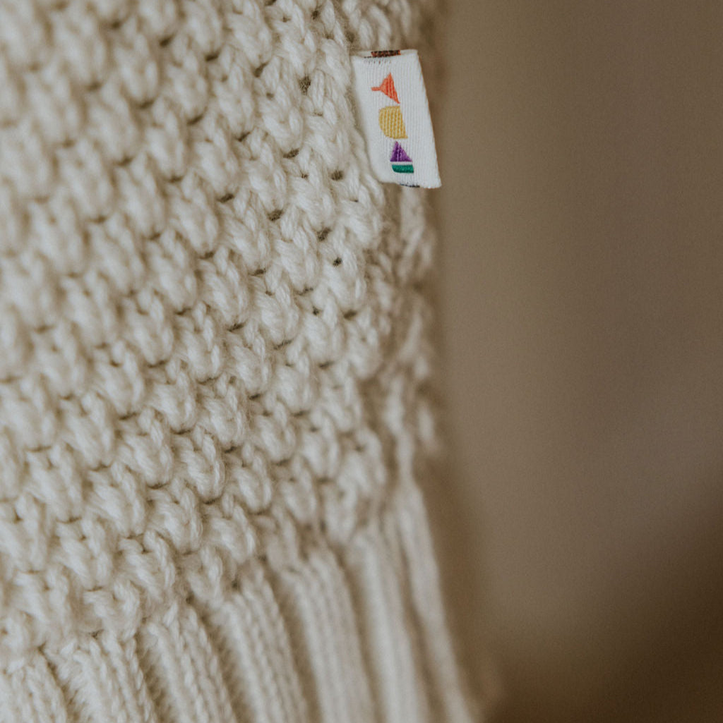 Ingezoomde foto van het witte gebreide materiaal van een trui van Yuki